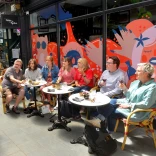 Group of people sitting a a table eating and drinking on a food tour in a shopping arcade.